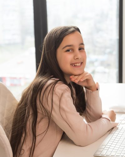 Home schooling. A girl is sitting at a table with a laptop during an online video chat of a school lesson with a teacher and class. Concept of distance education. Self-isolation in quarantine